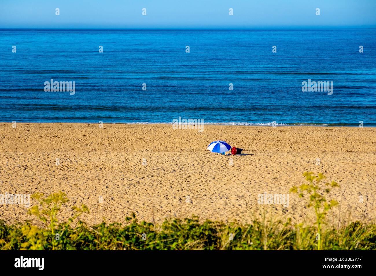 Sonnenschirm am ansonsten leeren Strand von Traeth Lligwy auf Anglesey / Ynys Mon, Wales, UK Stockfoto
