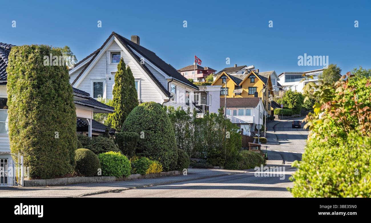Friedliche Nachbarschaft mit charmanten Häusern mit einzigartiger Architektur, üppigen Gärten und klarem Himmel. Malerische Aussicht auf eine ruhige Wohngegend Show Stockfoto