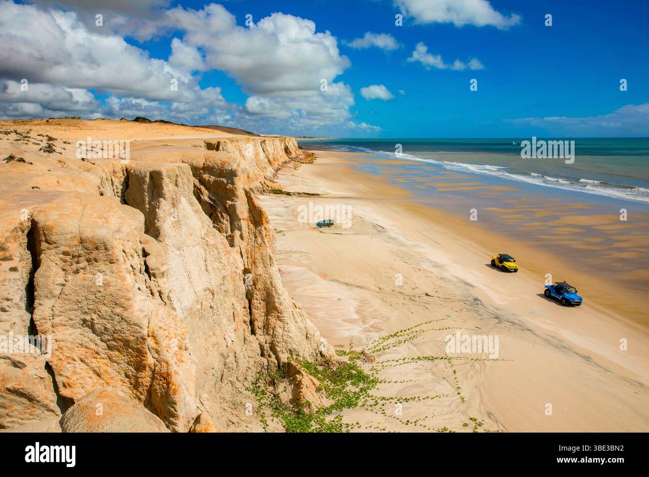 Brasilien, Nordeste, Ceara, Morro Branco Beach, Buggys, die entlang eines unberührten Strandes zwischen erodierten Klippen und dem Atlantischen Ozean Rollen Stockfoto