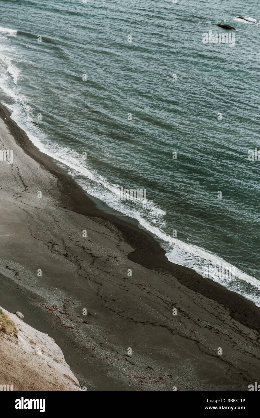 Wellen schlagen sanft gegen die schwarze Sandküste von Fauskasandur, Island. Stockfoto