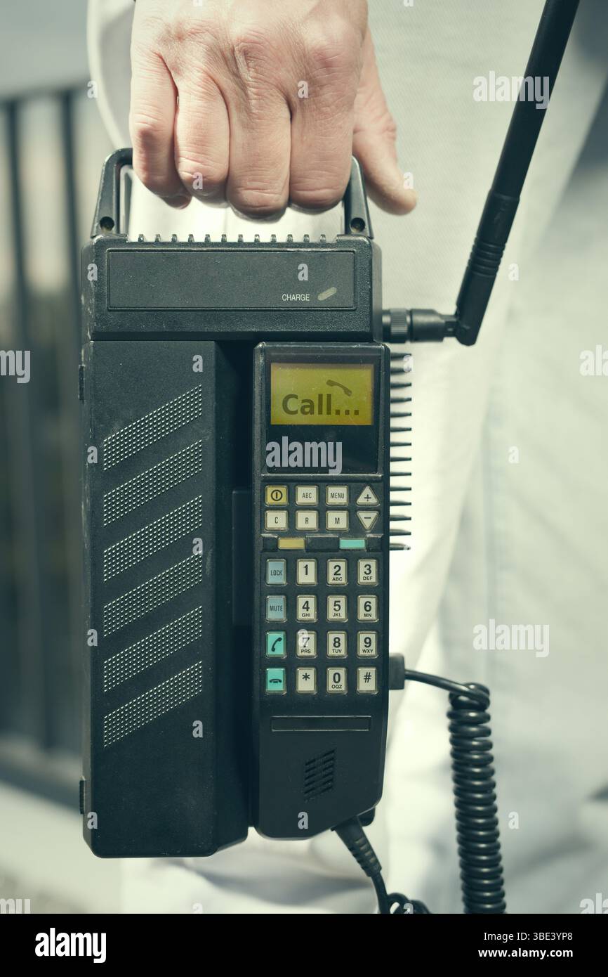 Älterer Mann draußen auf der Brücke, der ein Retro-Handy benutzt, um anzurufen Stockfoto