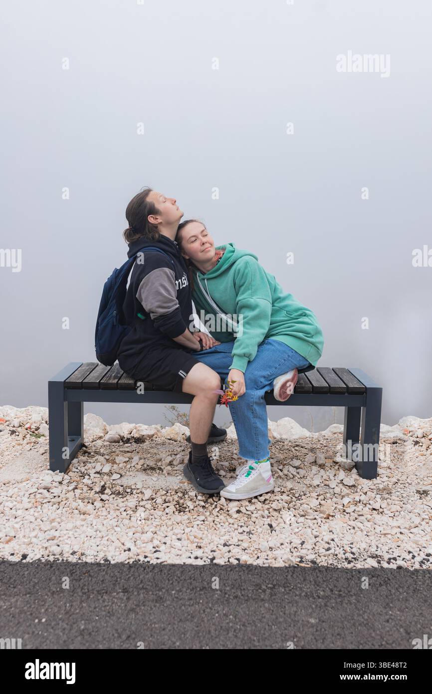 Ein Paar lehnende Köpfe zusammen auf einer Bergbank in dickem Nebel Stockfoto