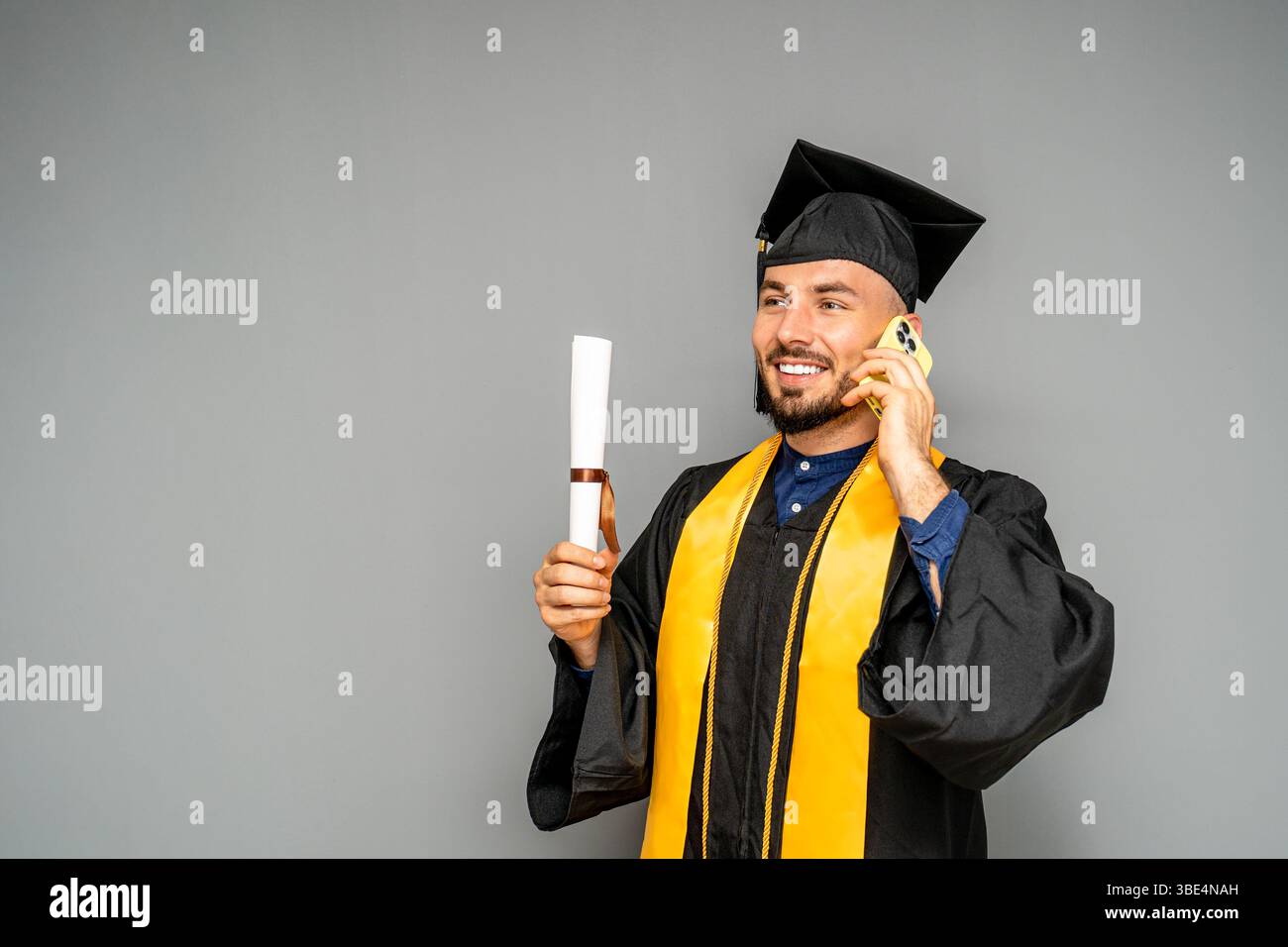 Glücklicher Absolvent, der nach der Abschlussfeier einen Anruf macht Stockfoto