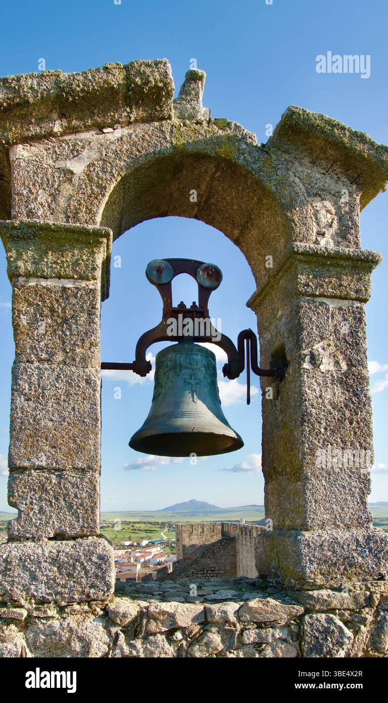 Blick auf die Landschaft durch einen Bogen mit einer Glocke auf dem Höhepunkt der Alcazaba de Trujillo und dem fernen Hügel Trujillo Caceres Extremadura Spanien Europa Stockfoto