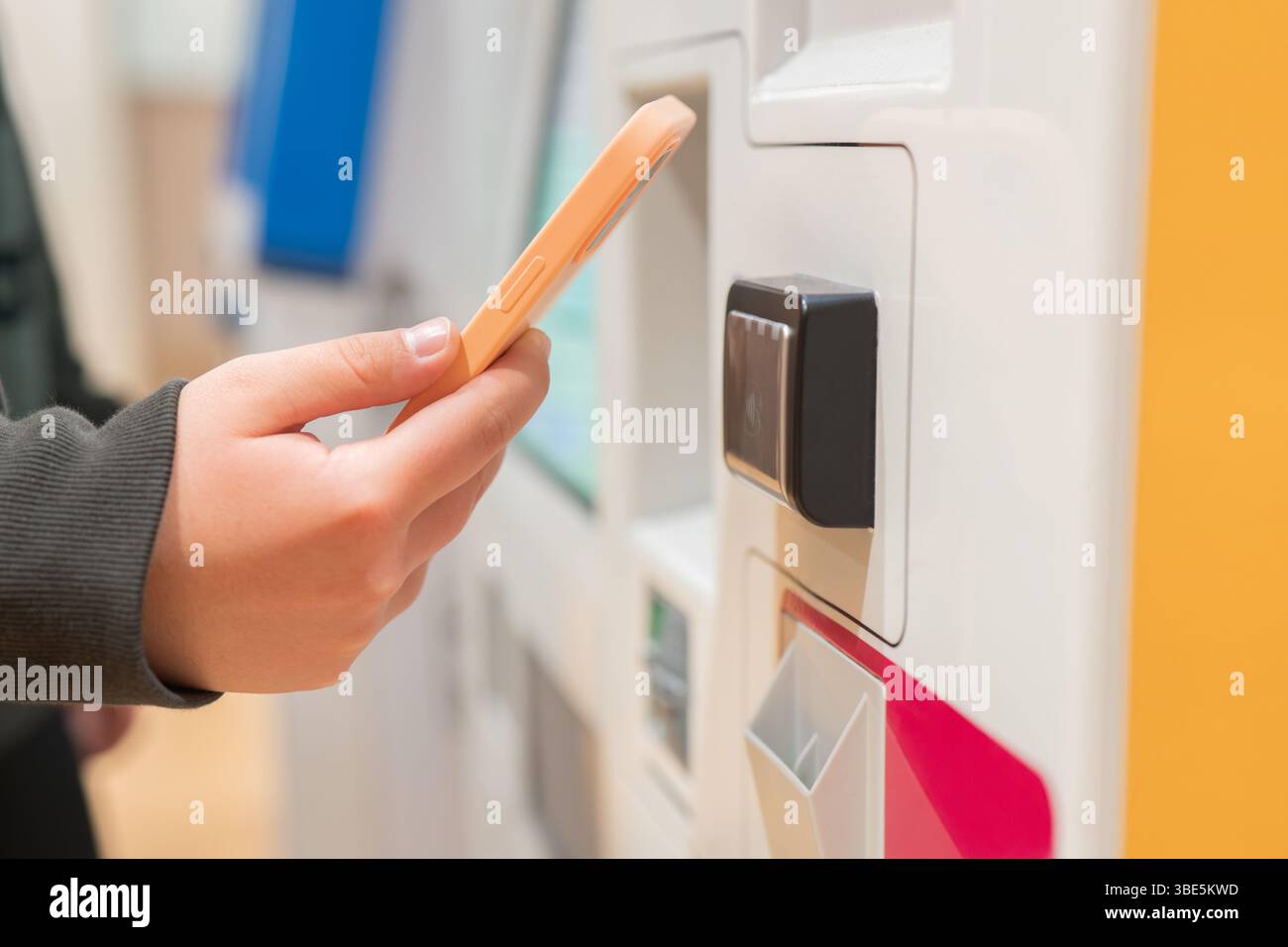 Ein Reisender verwendet ein mobiles Gerät, um mit einem Ticketkiosk an einem Flughafen zu interagieren. Das Bild erfasst den modernen Komfort der kontaktlosen Technologie in Stockfoto