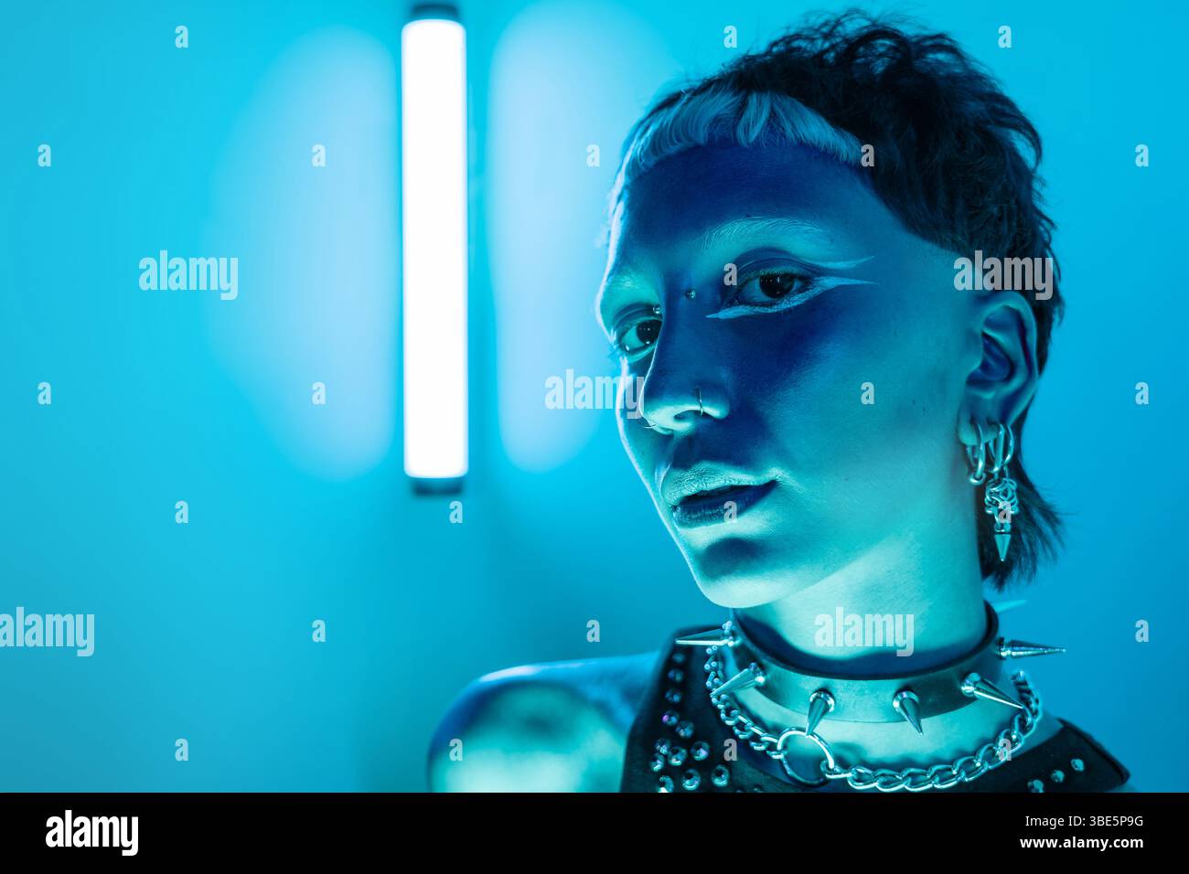 Eine eindrucksvolle Darstellung eines Cyberpunk-Frauenmodells in einem Neonlicht, das futuristische Mode mit detailliertem Make-up und Accessoires zeigt Stockfoto