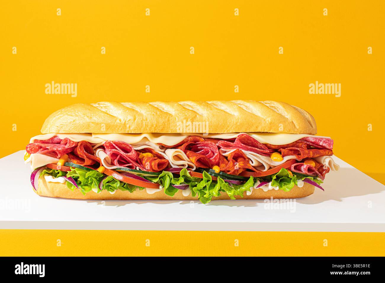 Frontalansicht eines U-Boot-Sandwiches, horizontal dargestellt mit Schichten aus Fleisch und frischem Gemüse, aufgenommen im Studio mit sanfter, ausgewogener Beleuchtung Stockfoto