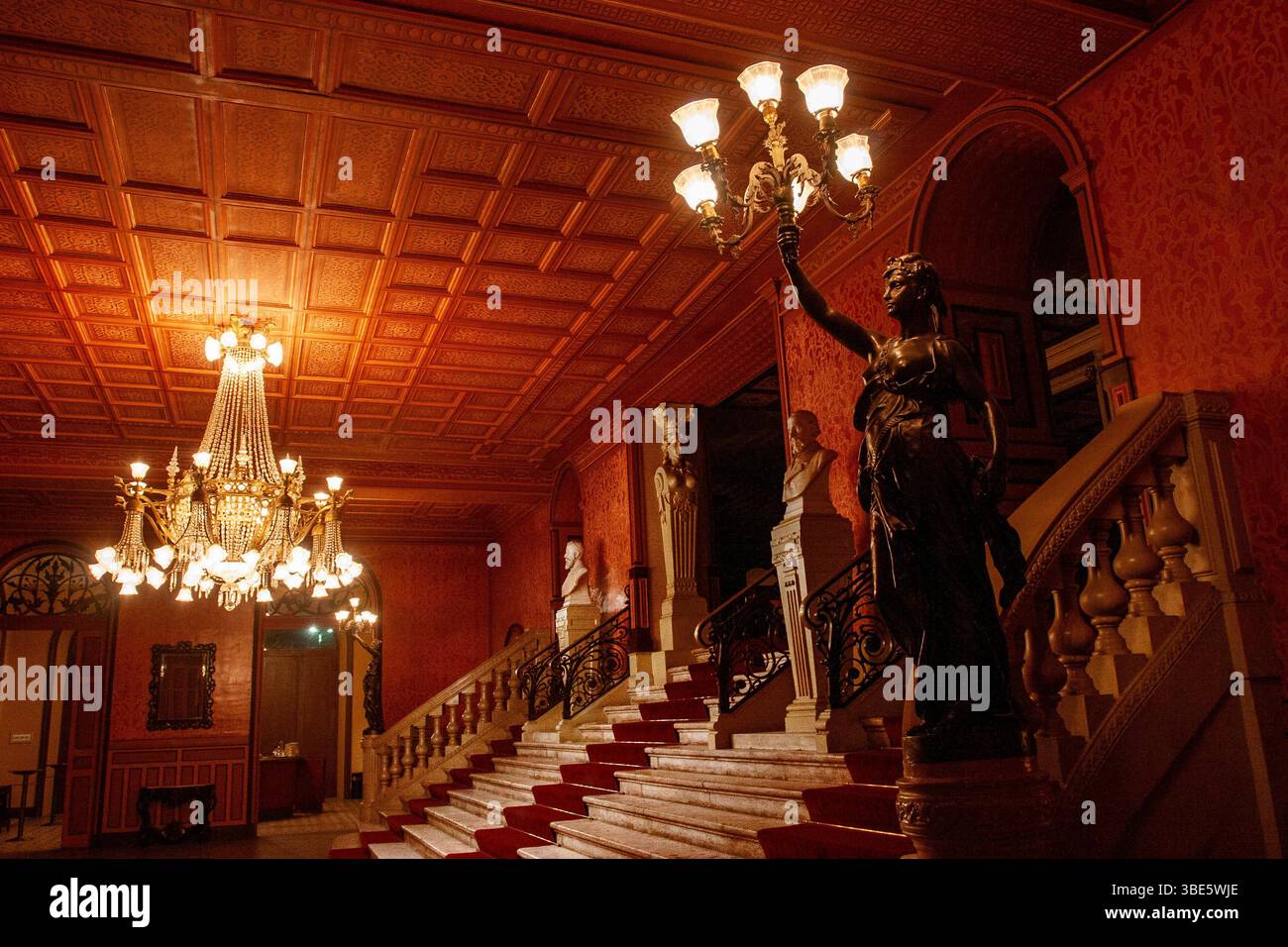 Die große Marmortreppe des Theatro da Paz in Belém, Pará, beleuchtet von einem verzierten zentralen Kronleuchter und flankiert von bronzenen Fackelstatuen. Stockfoto