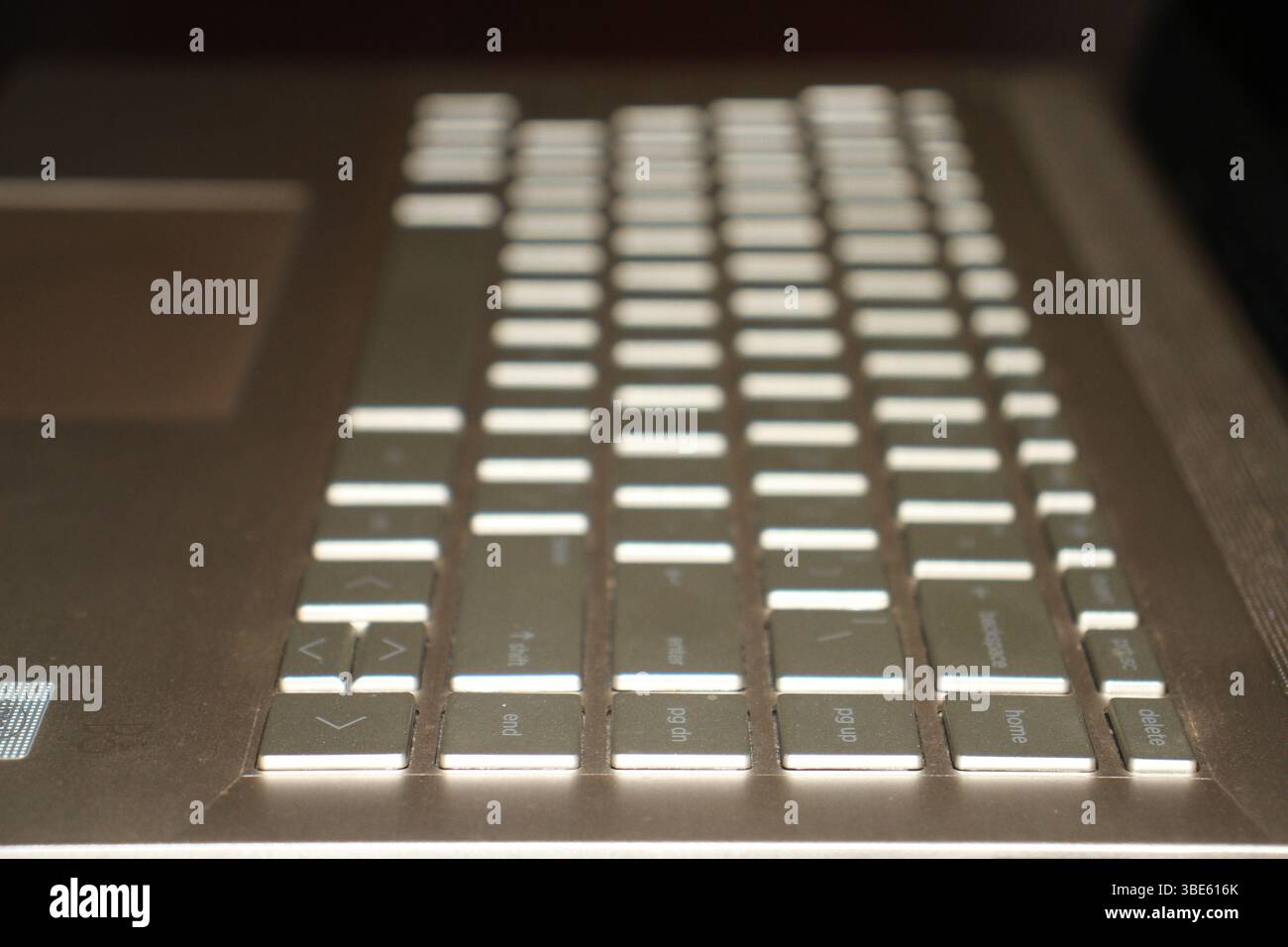 Eine goldfarbene Tastatur eines Laptops mit verschwommenem Hintergrund in hellem Licht auf einer Oberfläche. Stockfoto