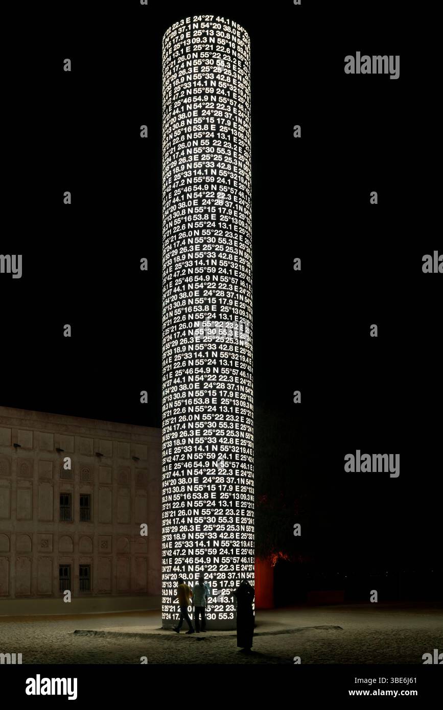 Ein hoher Kunstzylinder mit dem Titel „Directions“ mit beleuchteten Koordinaten steht nachts auf Samaliyah Island in Abu Dhabi VAE. Stockfoto