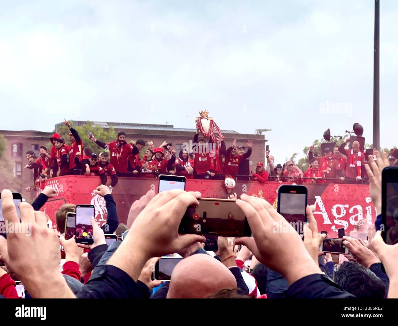 Die Spieler des FC Liverpool feiern im offenen Bus mit der Trophäe der Premier League während der Siegerparade in der Strand Street, Liverpool, Großbritannien. 26. Mai 2025. - Smartphone-aufgenommenes Stockfoto