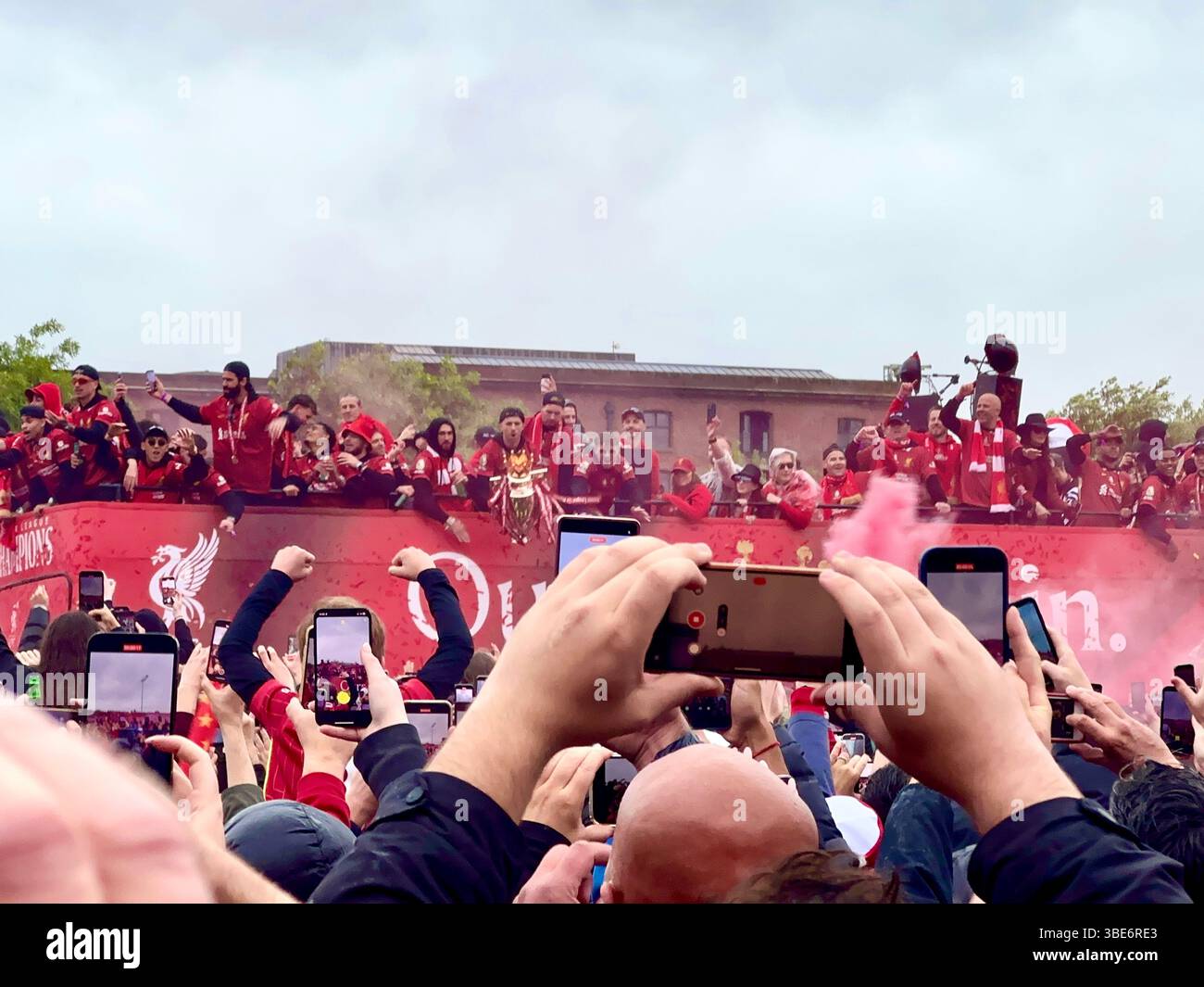 Die Spieler des FC Liverpool feiern im offenen Bus mit der Trophäe der Premier League während der Siegerparade in der Strand Street, Liverpool, Großbritannien. 26. Mai 2025. - Smartphone-aufgenommenes Stockfoto