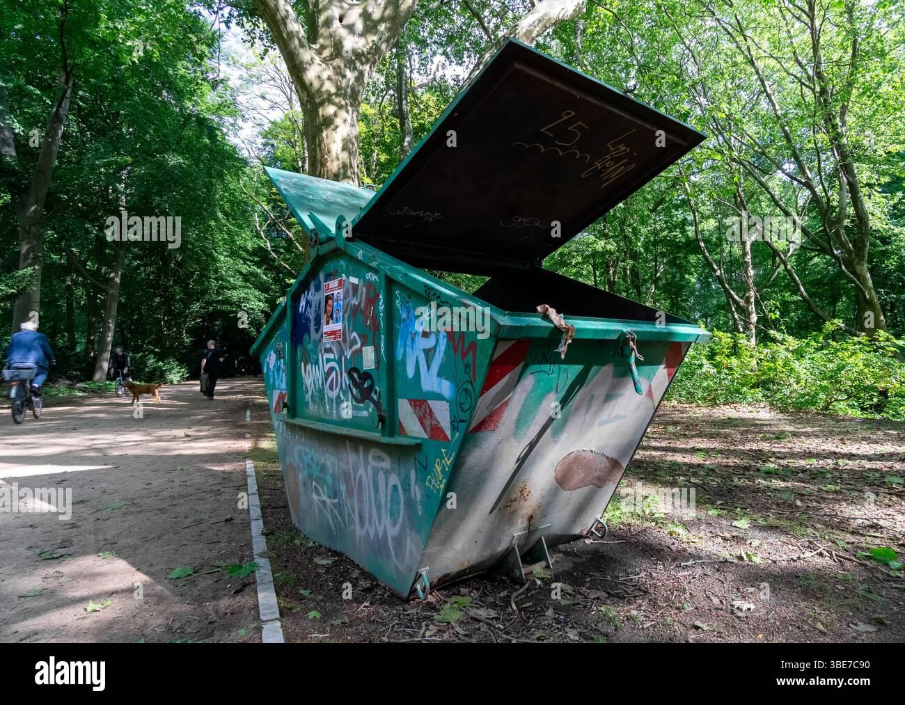 Offener grüner Überwurfcontainer mit Graffiti steht auf einem Waldweg im Berliner Tiergarten, der für Parkpflege und -Sanierung genutzt wird. Stockfoto