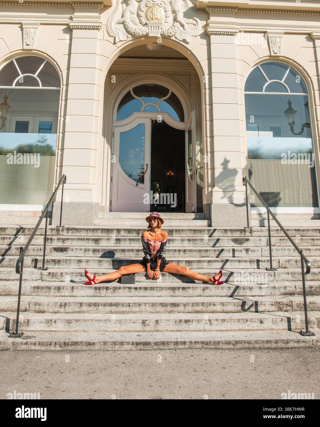 Porträt einer schönen Frau, die auf der Treppe vor dem Casino in Luzern, Schweiz, sitzt. Das Modemodell macht sich auf aktive Reisen. Stockfoto