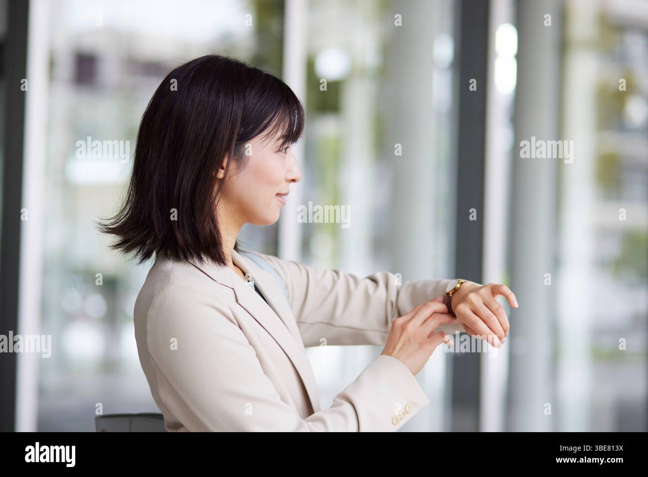 Japanische Geschäftsfrau überprüft die Zeit auf ihrer Armbanduhr Stockfoto