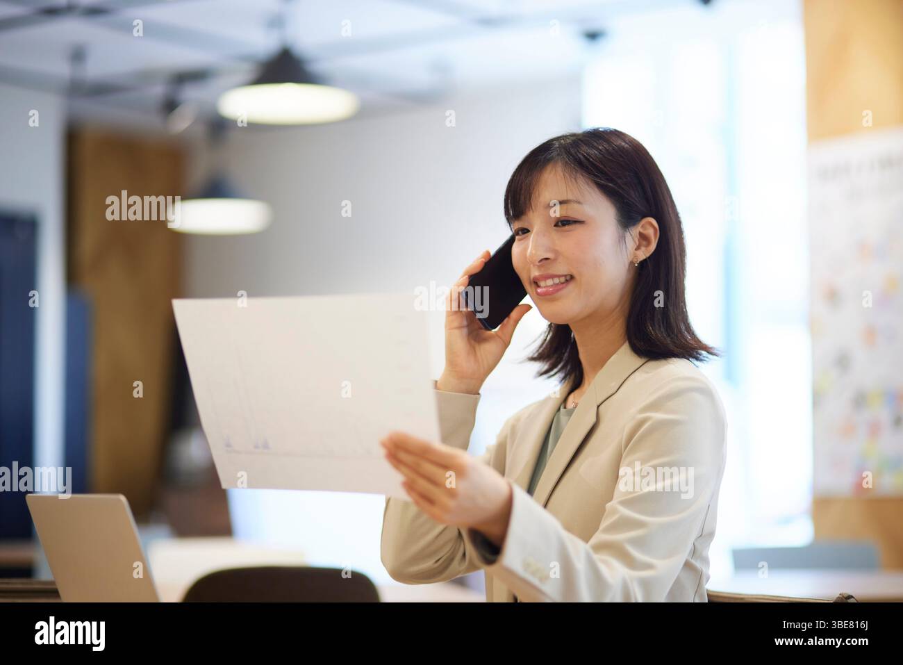 Japanerin, die im Büro mit ihrem Smartphone telefoniert Stockfoto