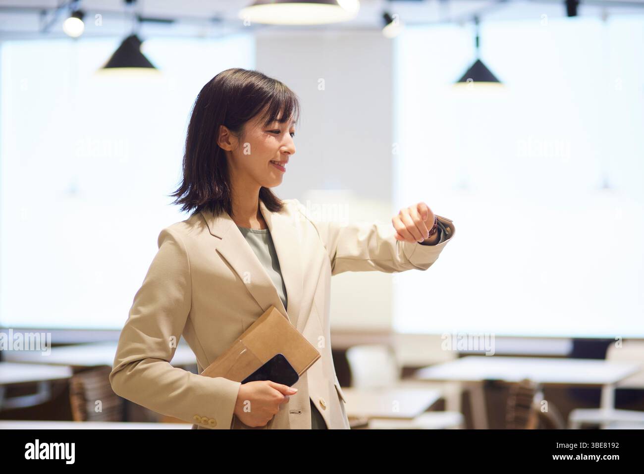 Japanerin im Anzug, die ihre Uhr im Büro überprüft Stockfoto