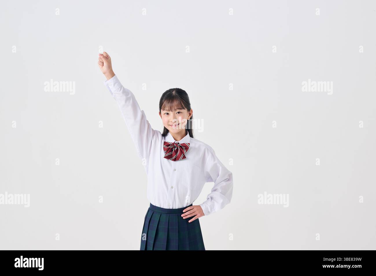 Japanisches Highschool-Mädchen, das die Faust auf weißem Hintergrund hält Stockfoto