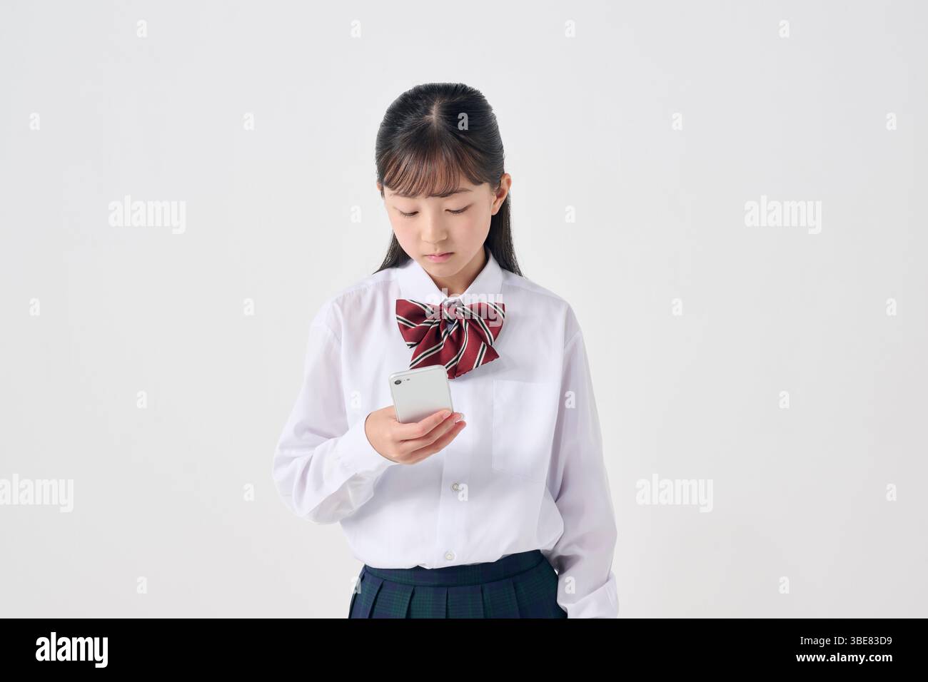 Japanische Schülerin der Sekundarstufe mit Smartphone, weißer Hintergrund Stockfoto