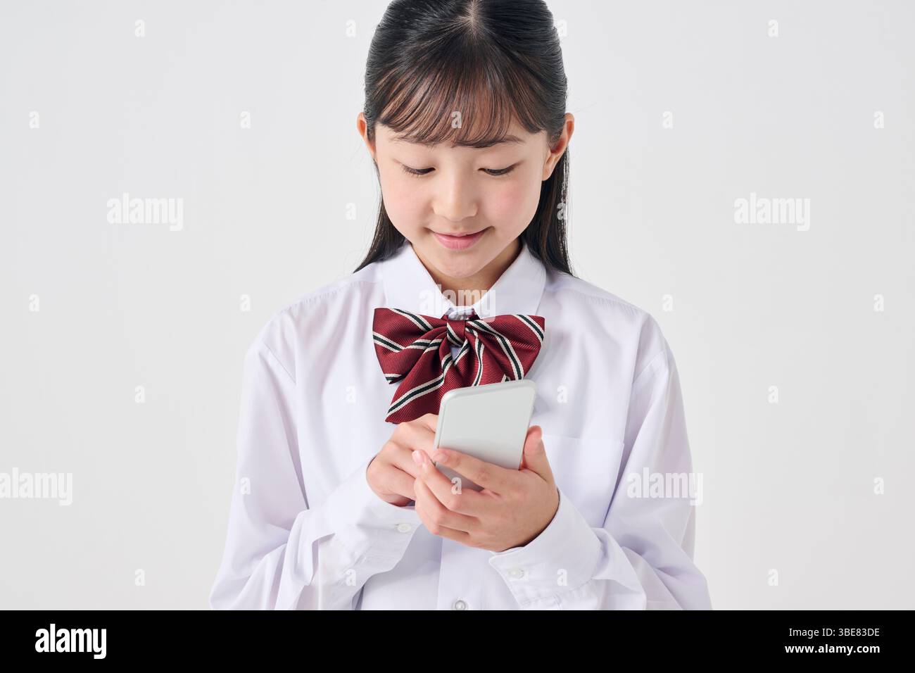 Japanische Schülerin der Sekundarstufe mit Smartphone, weißer Hintergrund Stockfoto