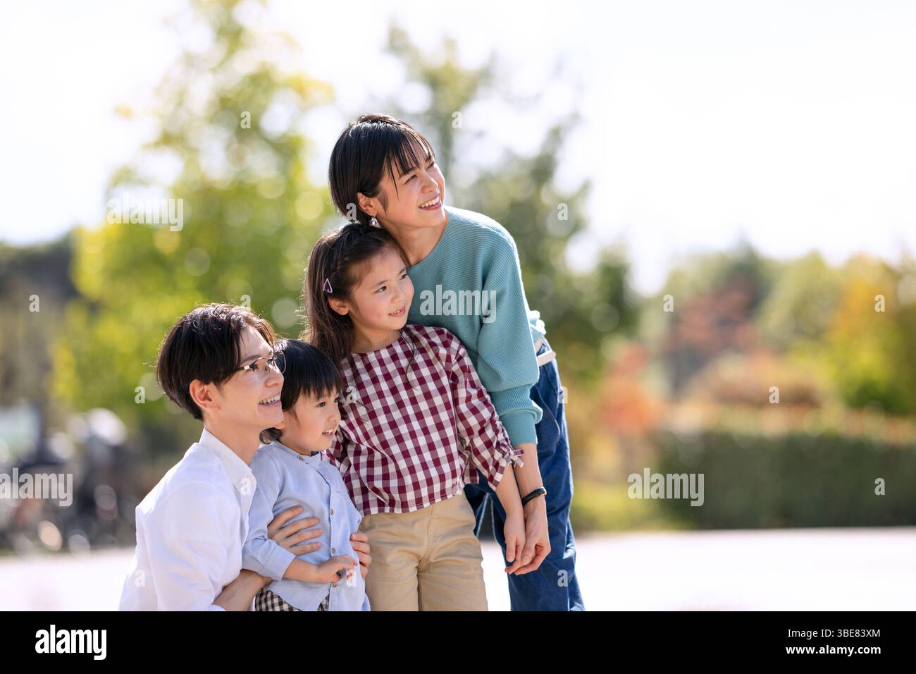 Vierköpfige Familie mit Blick weit weg im Park Stockfoto