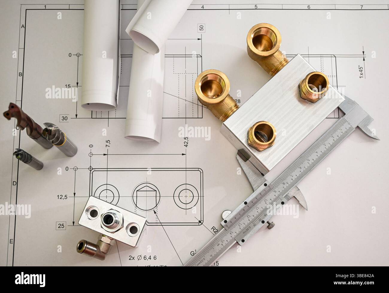 Metallinstallationsvorrichtung, Bremssattel und Bohrer liegen während einer Qualitätskontrolle in einem Fertigungswerk auf einem Plan. Stockfoto