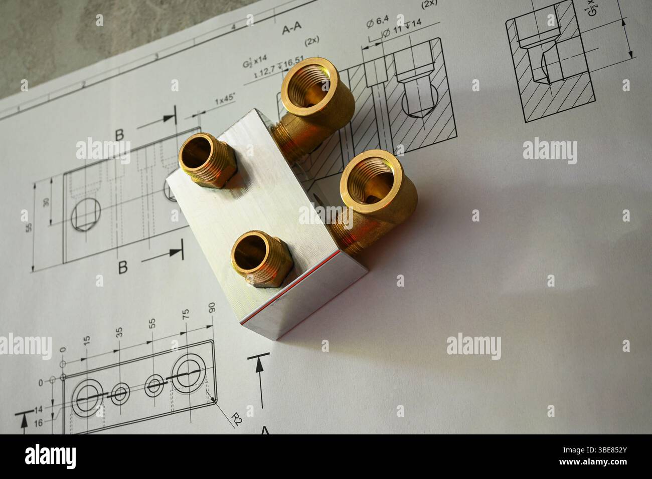 Messinginstallationen, die auf einer technischen Zeichnung oder einem Entwurf liegen und die Präzision in Fertigung und Konstruktion demonstrieren. Stockfoto