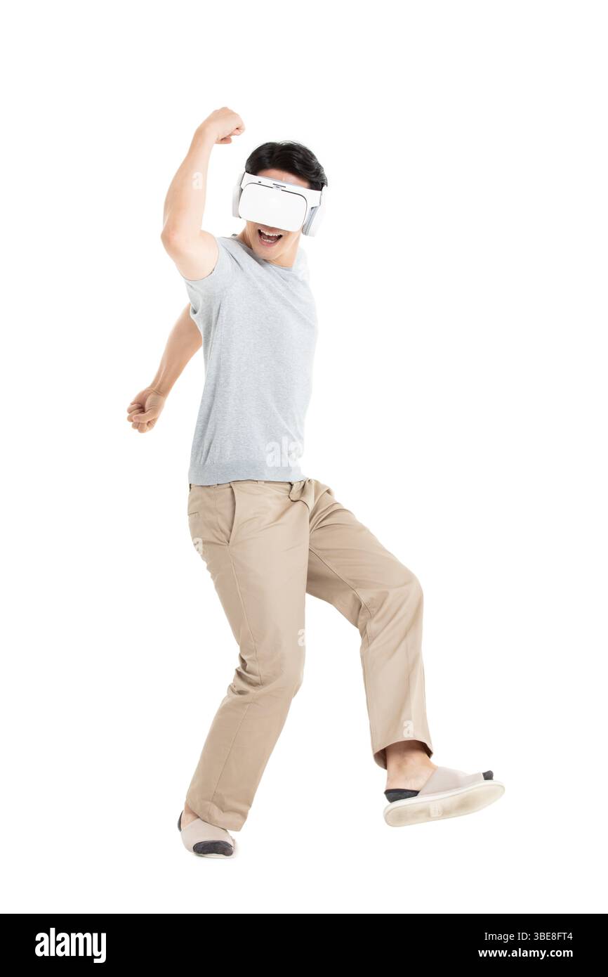 Ein junger Mann, der ein VR-Headset trägt und sich in immersiver Mensch-Maschine-Interaktion einsetzt Stockfoto