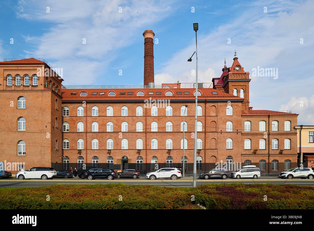 Ein historisches Industriegebäude aus rotem Backstein, das ein markantes, hoch stehendes Schornsteingebäude zeigt Stockfoto