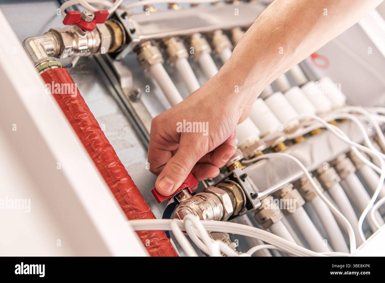 Ein Techniker arbeitet an einem Rohrleitungssystem, stellt Ventile ein und stellt in einer kontrollierten Umgebung ordnungsgemäße Anschlüsse sicher. Stockfoto