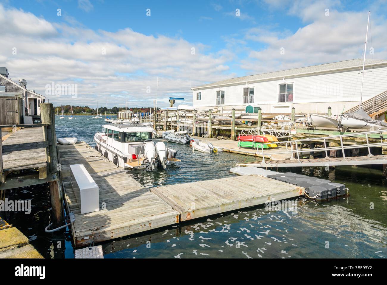 Boote, die an einem sonnigen Herbsttag auf einem Holzpier in einem Hafen an schwimmenden Stegen und Jollen ankerten Stockfoto