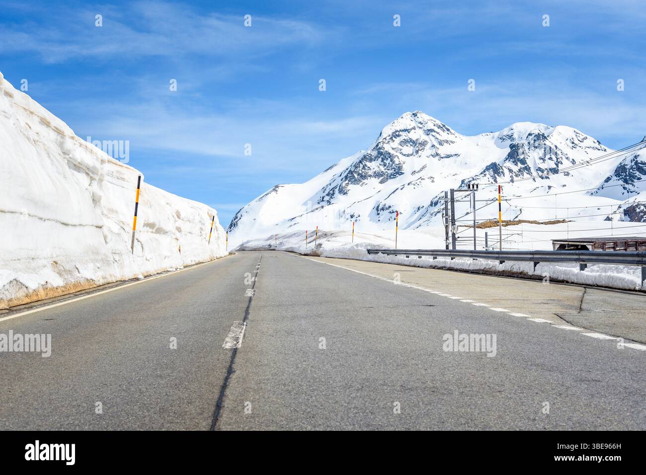 Leerer Abschnitt einer Passstraße durch eine verschneite Landschaft unter blauem Himmel im Frühjahr Stockfoto