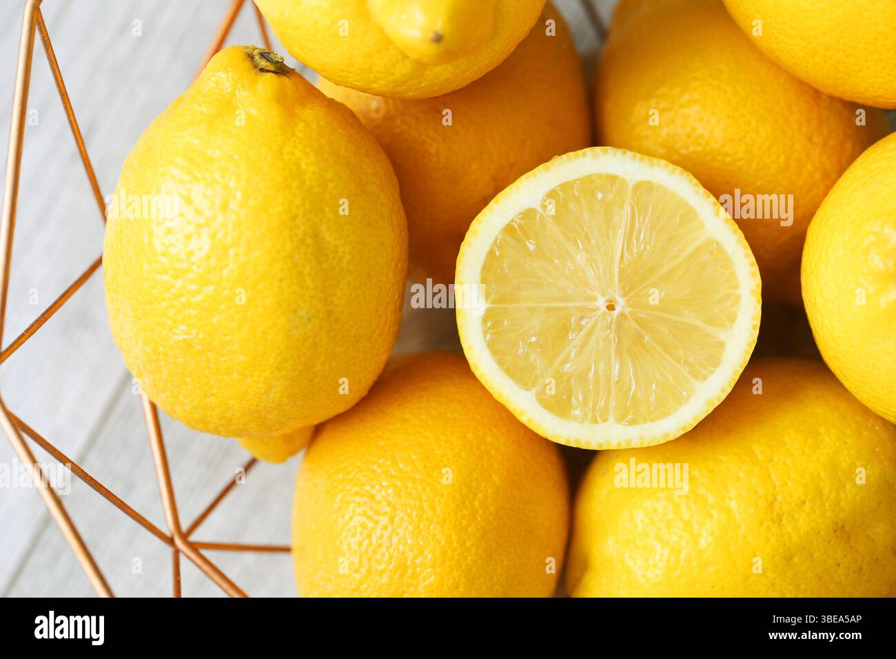 Frische gelbe Zitronen. In Scheiben geschnittene Zitrone in der Mitte. Hintergrund der Zitrusfrüchte. Leuchtende, lebendige Textur. Natürliche Vitamin-C-Quelle. Saftiges und gesundes Essen. Stockfoto