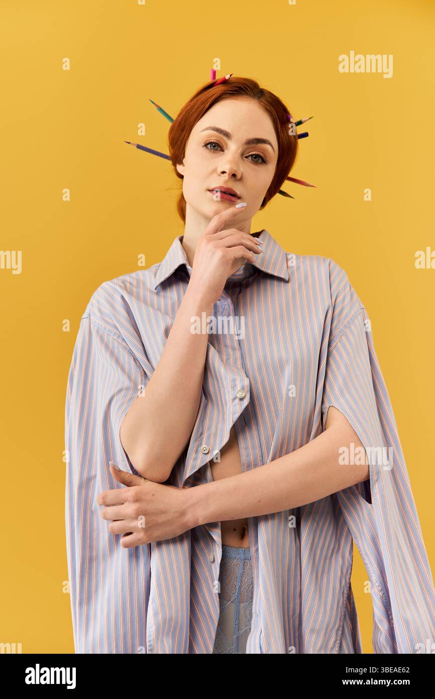 Eine schöne Frau posiert nachdenklich mit dem Kinn auf ihren Fingern vor einem gelben Hintergrund. Stockfoto