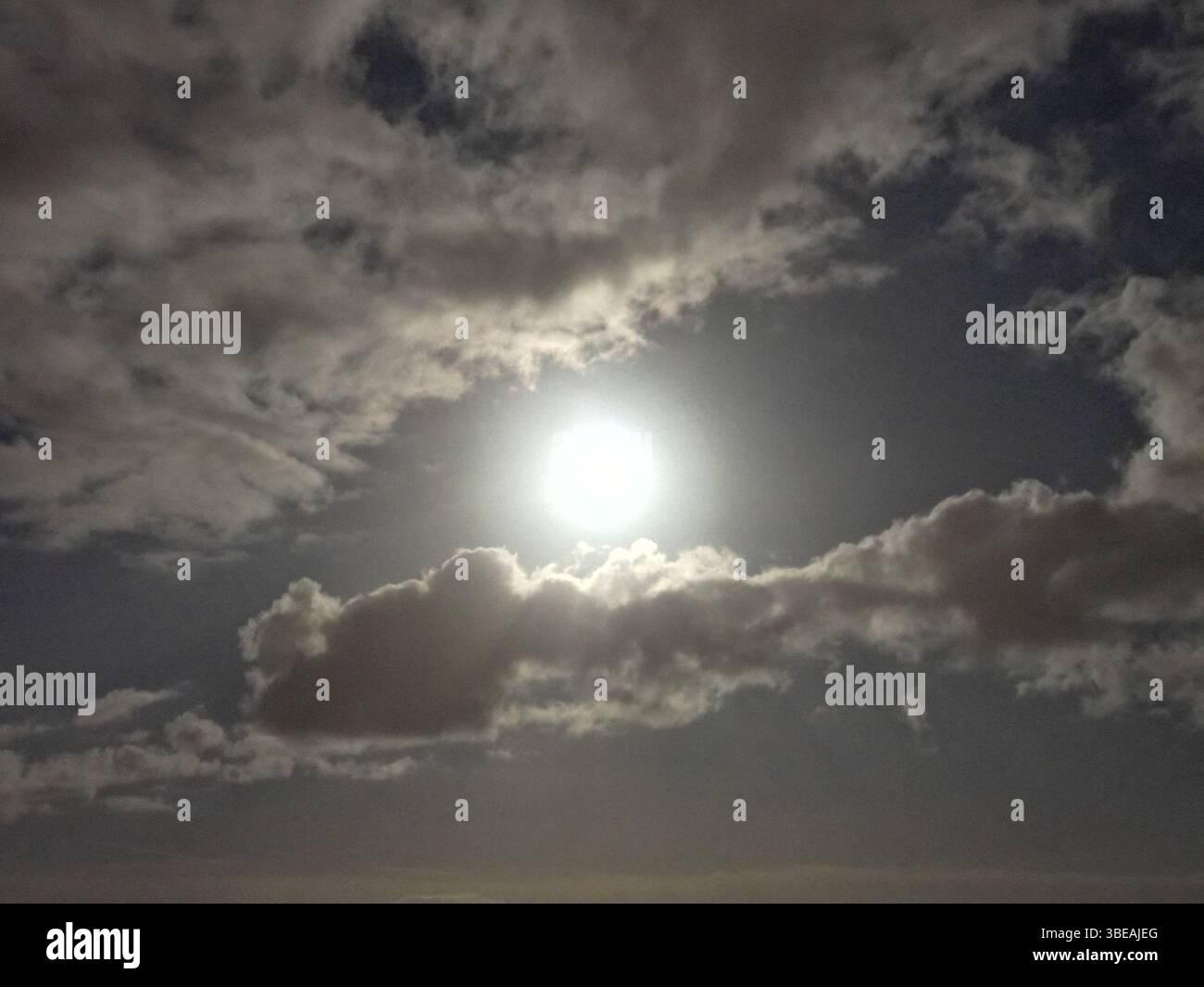 Nahaufnahme des Vollmonds, teilweise von Wolken über Nottingham, Großbritannien, bedeckt, bei Nacht mit dramatischem Kontrast und einem filmischen, stimmungsvollen Ton. Stockfoto