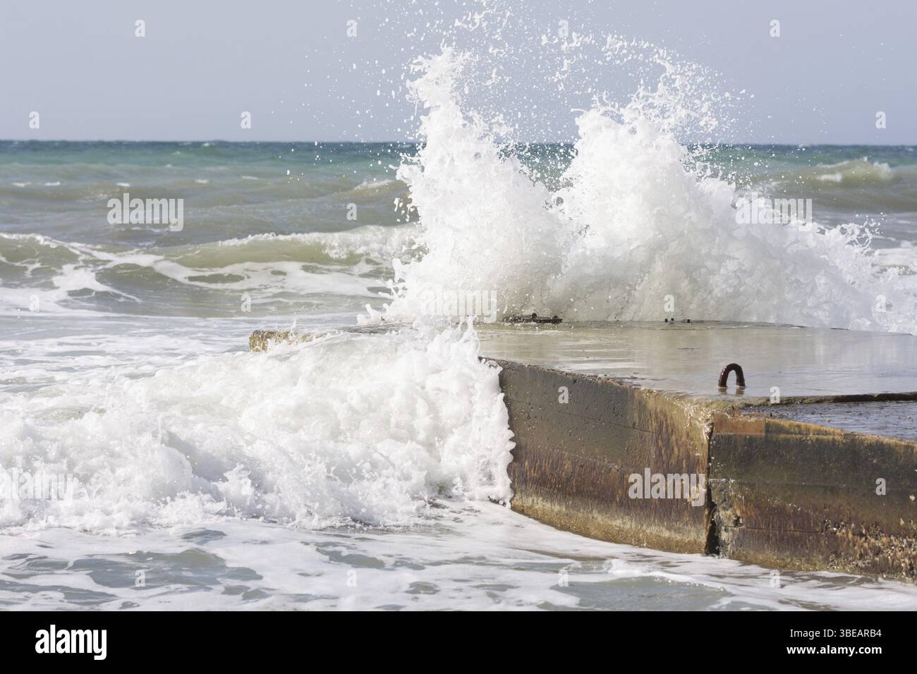 Meereswellen brechen sich am konkreten pier Stockfoto