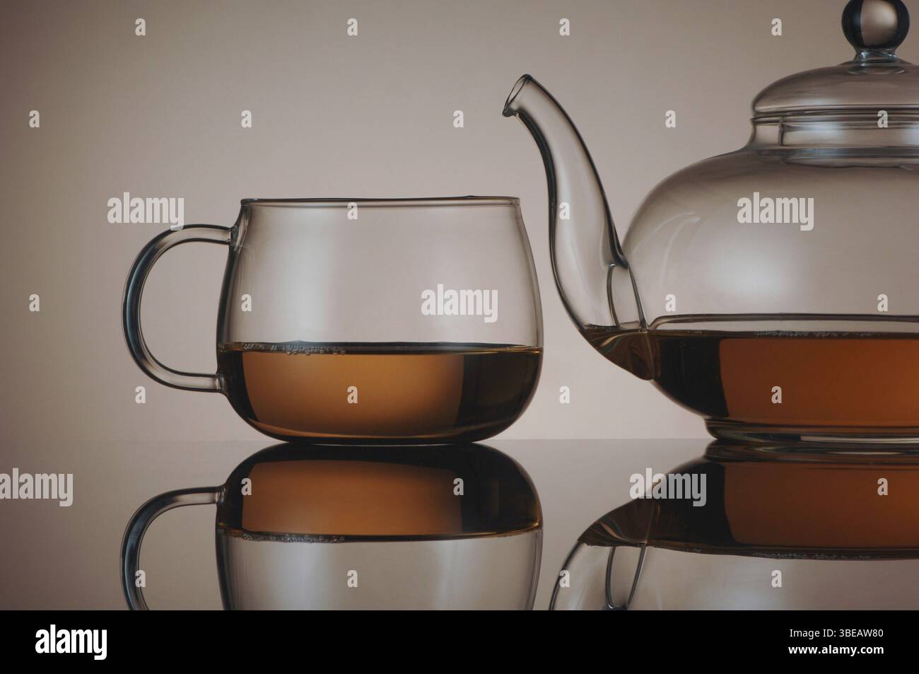 Teekanne aus transparentem Glas und Teetasse mit Reflexion Stockfoto