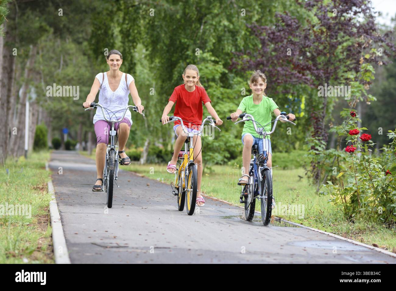 Mama mit zwei Kindern fahren im Park mit dem Fahrrad Am Morgen Stockfoto