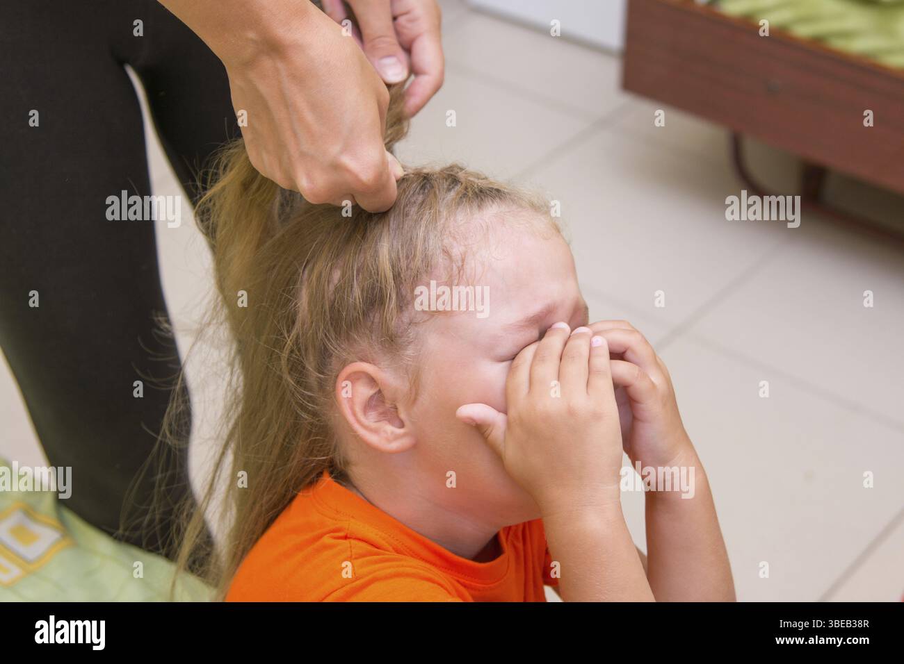 Das kleine Mädchen weinte, wenn sie langes Haar geflochten Stockfoto