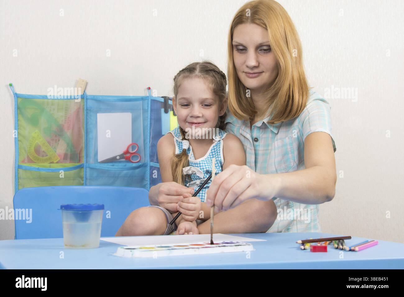 Eine fünfjähriges Mädchen beschäftigt sich mit Zeichnung mit Erwachsenen jungen schönen Mädchen sitzen am Tisch zu Hause Kinder Stockfoto