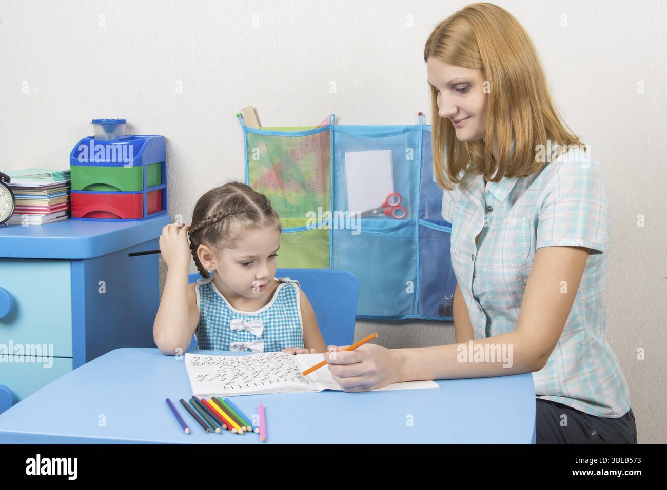 Eine fünfjähriges Mädchen engagiert sich Erwachsene junge schöne Mädchen sitzen am Tisch zu Hause Kinder Stockfoto