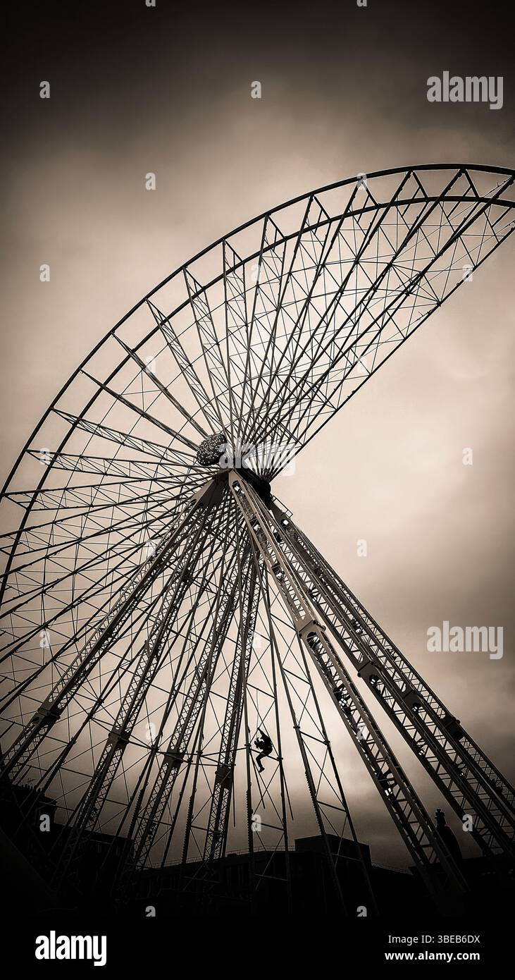 Ein Wartungspersonal kann die Struktur eines Riesenrads mit leuchtenden Lichtern besteigen. Stockfoto