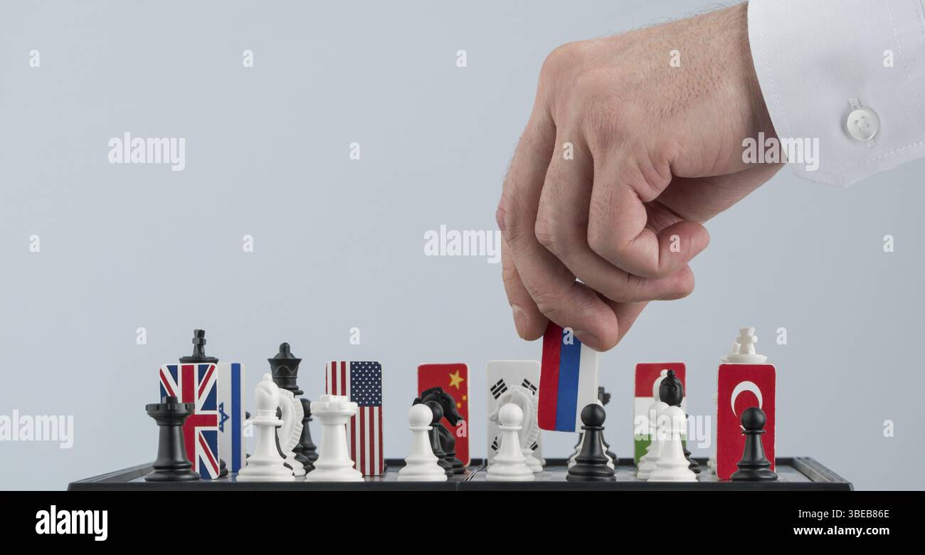 Der Politikerin aus der Hand bewegt sich eine Schachfigur mit einer Flagge. Konzeptionelle Foto von einem politischen Spiel. Vergeltungsmaßnahmen bewegen Russland Stockfoto