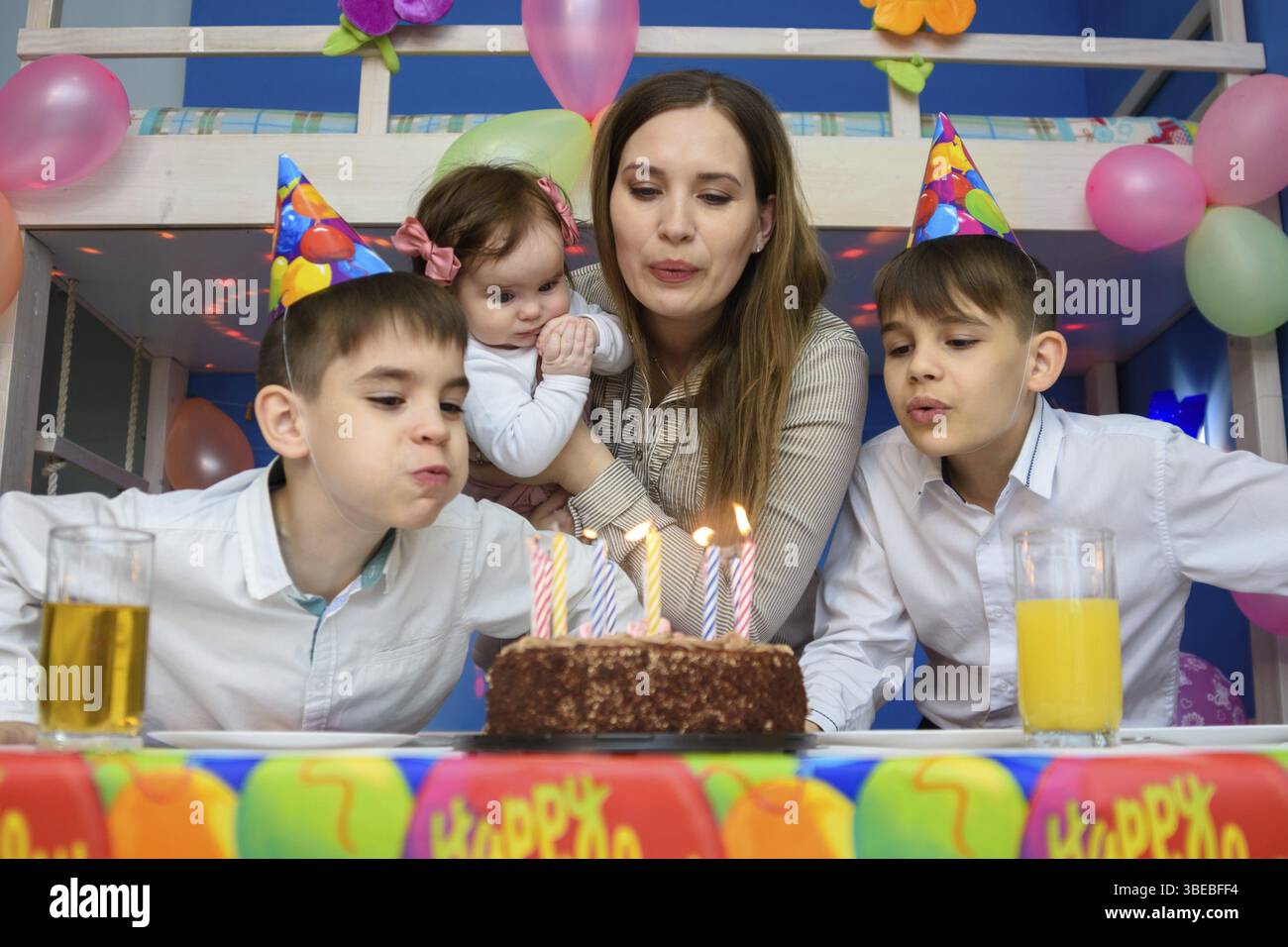 Familie bläst Kerzen auf Geburtstagskuchen Stockfoto