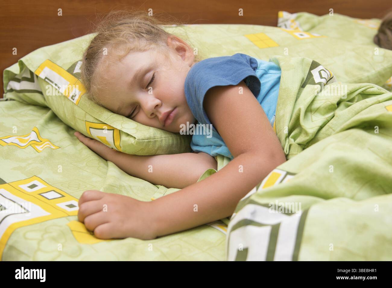 Kleines Mädchen schlafen auf ihrer Seite im Bett mit seiner Hand unter das Kopfkissen und mit einer Decke abgedeckt Stockfoto