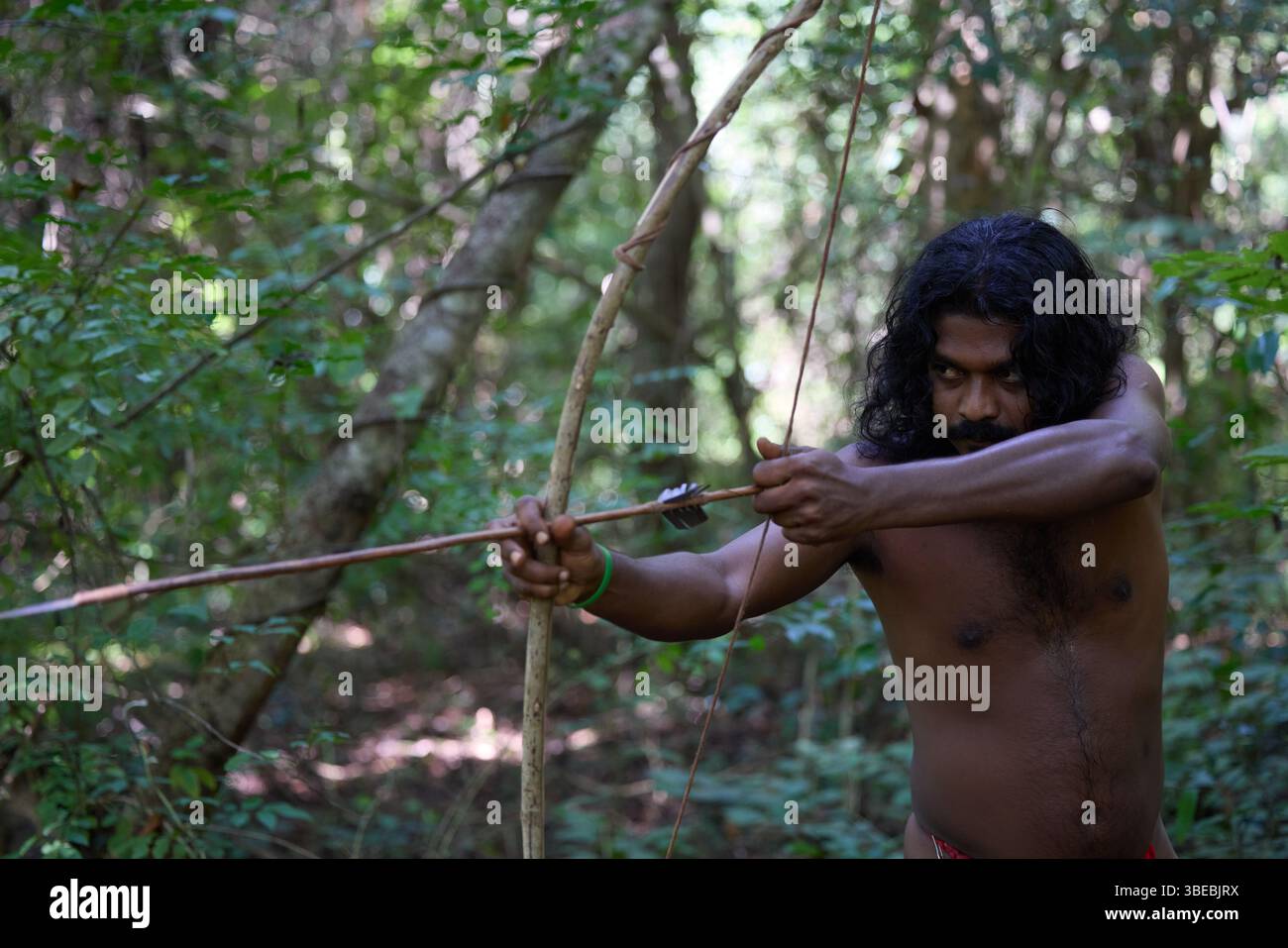 Vedda Stammesmann aus Sri Lanka jagt im Dschungel mit Bogen und Pfeil, traditionellem Lebensstil und Verbindung zur Natur. Stammesporträt im Einheimischen Stockfoto