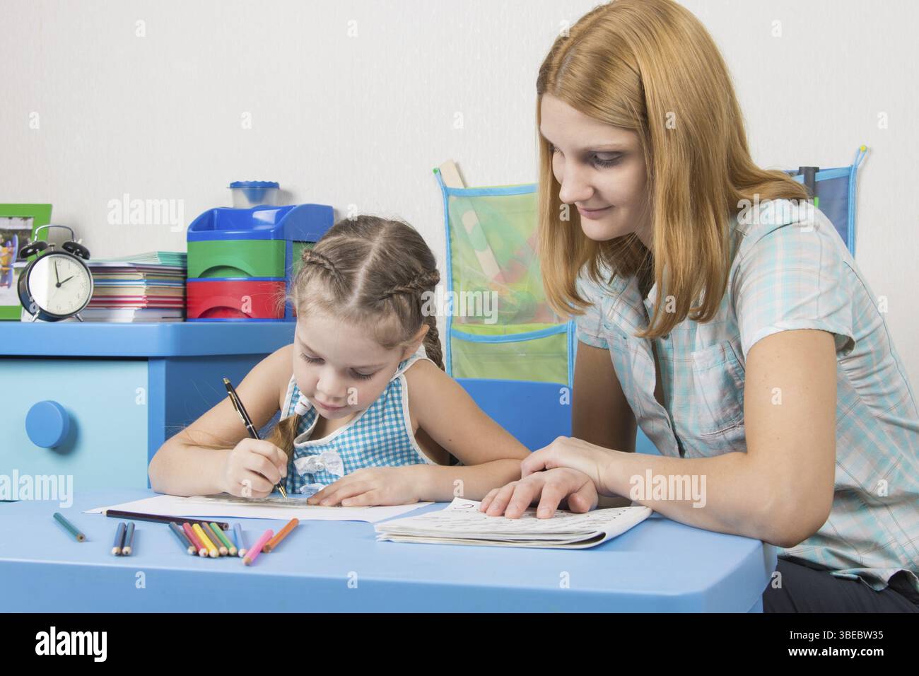 Eine fünfjähriges Mädchen engagiert sich Erwachsene junge schöne Mädchen sitzen am Tisch zu Hause Kinder Stockfoto