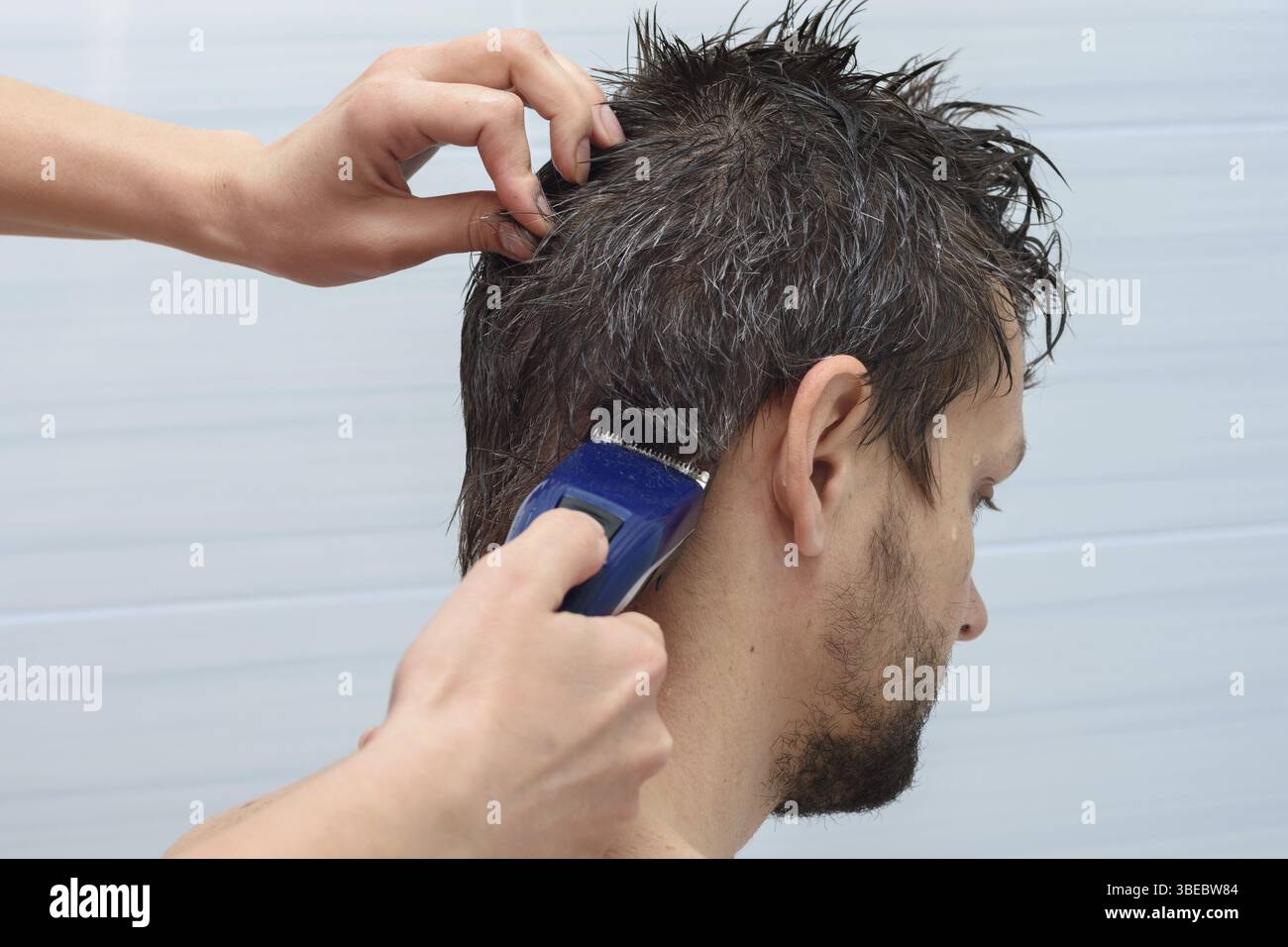 Der Friseur beginnt zu Hause die Haare auf dem kopf des mannes zu schneiden Stockfoto
