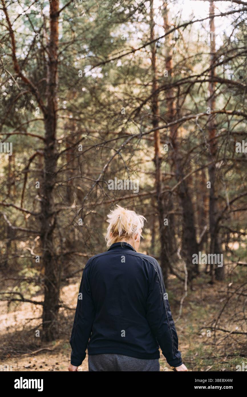 Frau im Wald an einem sonnigen Tag. Kiefern hoch. Naturnah, geistige Heilung mit frischer Luft. Digitale Detox, ohne die Natur zu verschlimmern. Überlebensfähigkeiten. Stockfoto