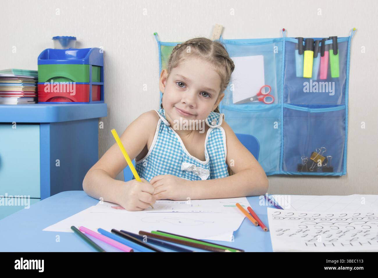 Glückliches fünf Jahre altes Mädchen zieht Bleistift und sah in den Rahmen Stockfoto